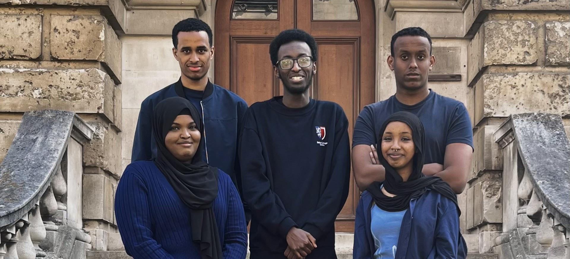 A group of students from the Oxford Somali Society sit on the steps of the Radcliffe Camera.