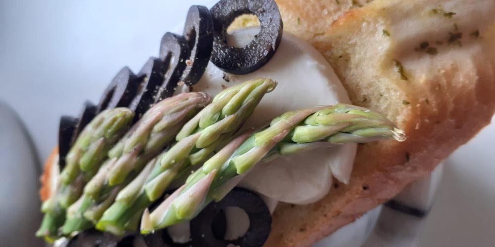A bruschetta with olive and asparagus topping.