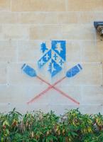 A chalked image of the Trinity College shield with boat club blades on the wall of a college building.