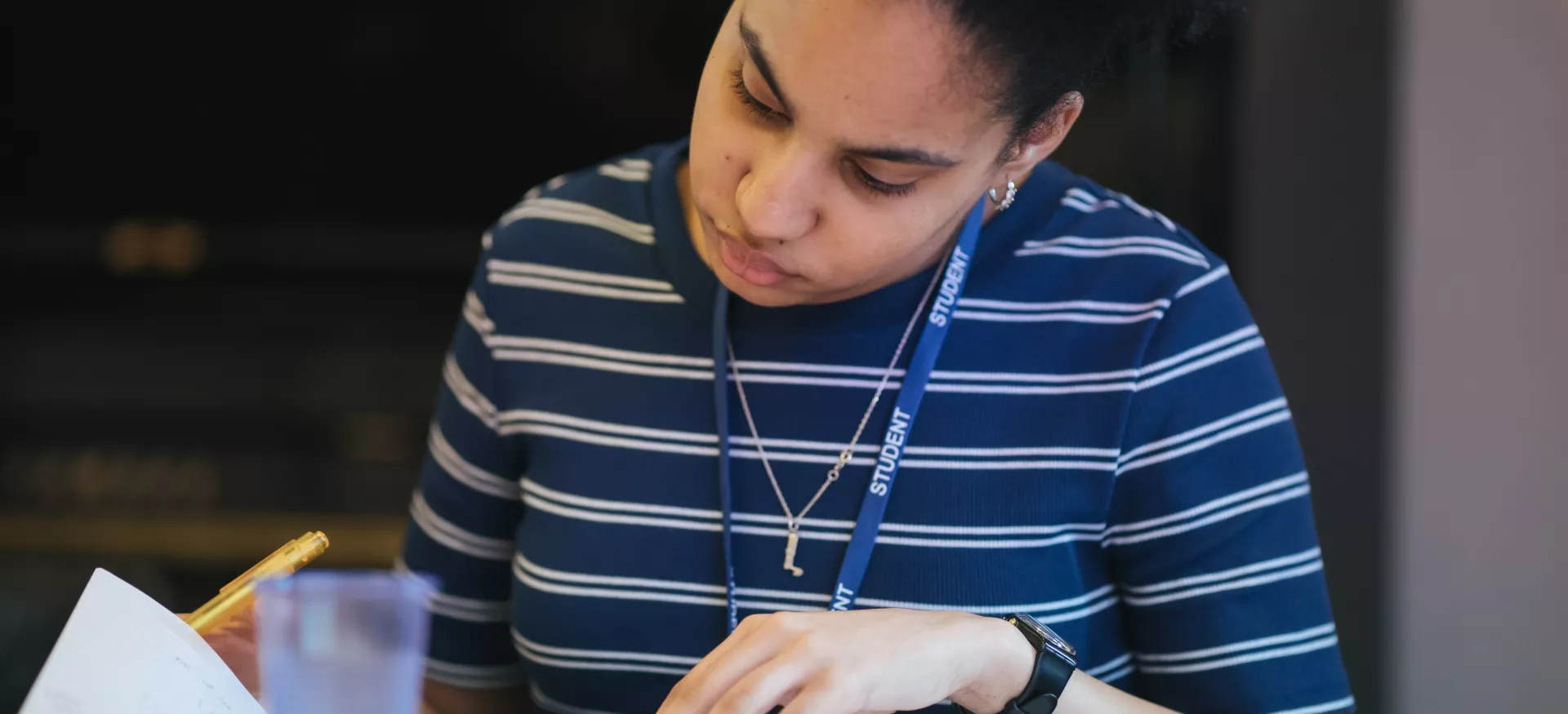 A female student consults a book while studying at a desk.