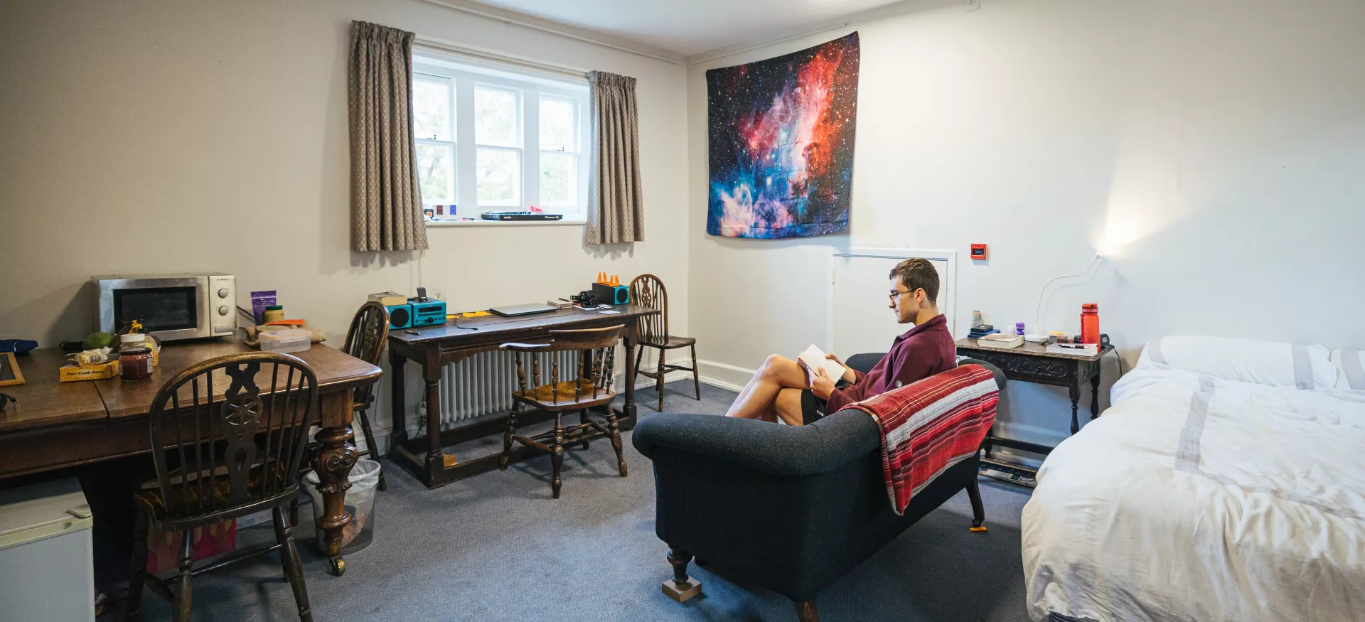 An student sits reading on the couch in a postgraduate room on Trinity's main site.