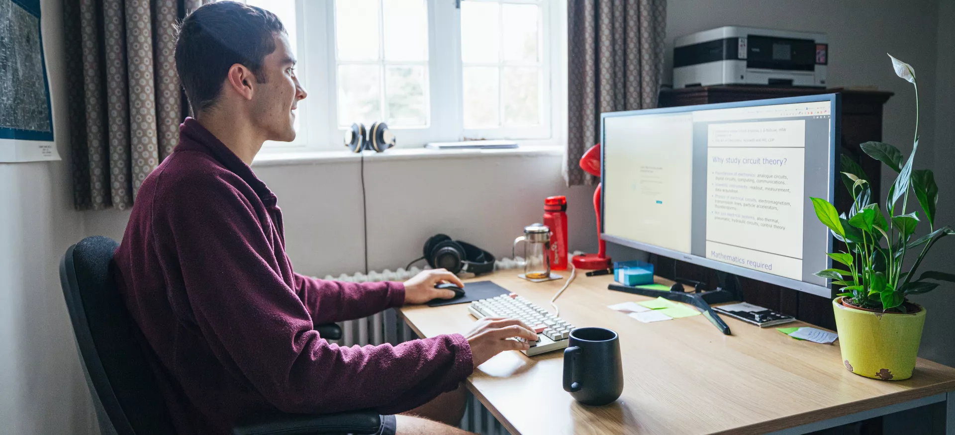 A postgraduate student sits studying at a desk. 