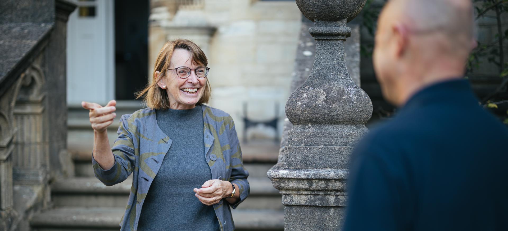Trinity college president Hilary Boulding stands outside gesturing while talking to one of the college porters.