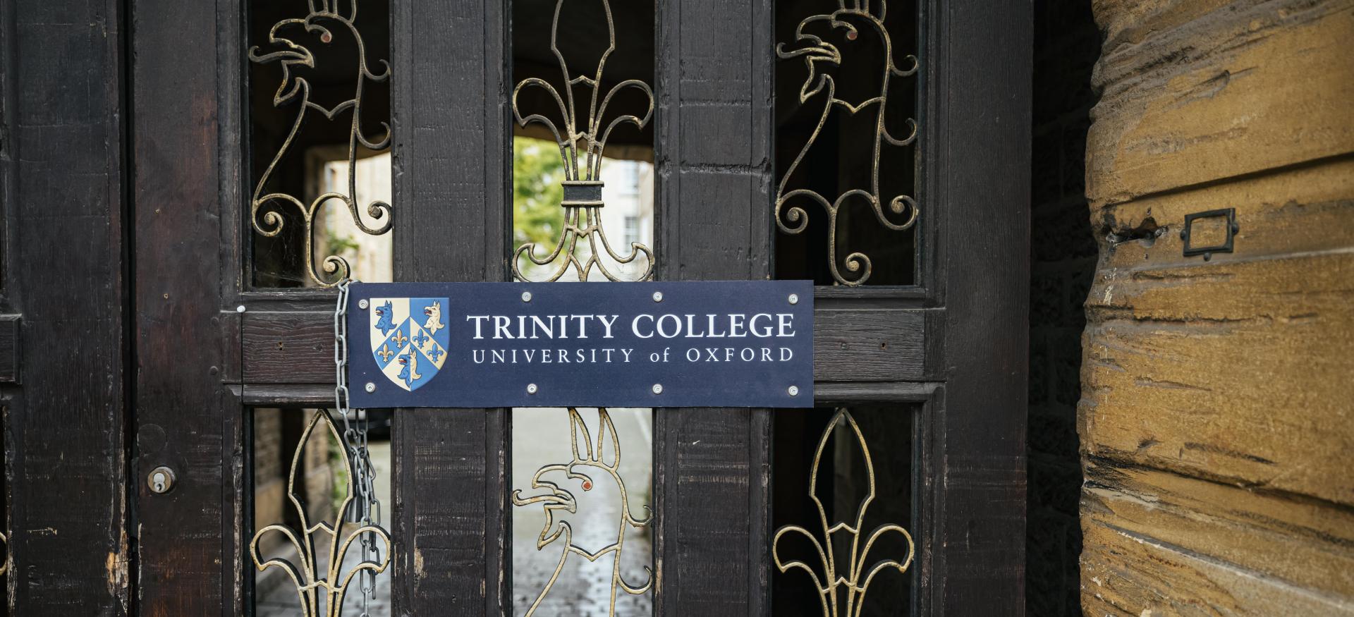 The side entrance to trinity College with ironwork in the shape of gryphons and a sign reading 'Trinity College Oxford'