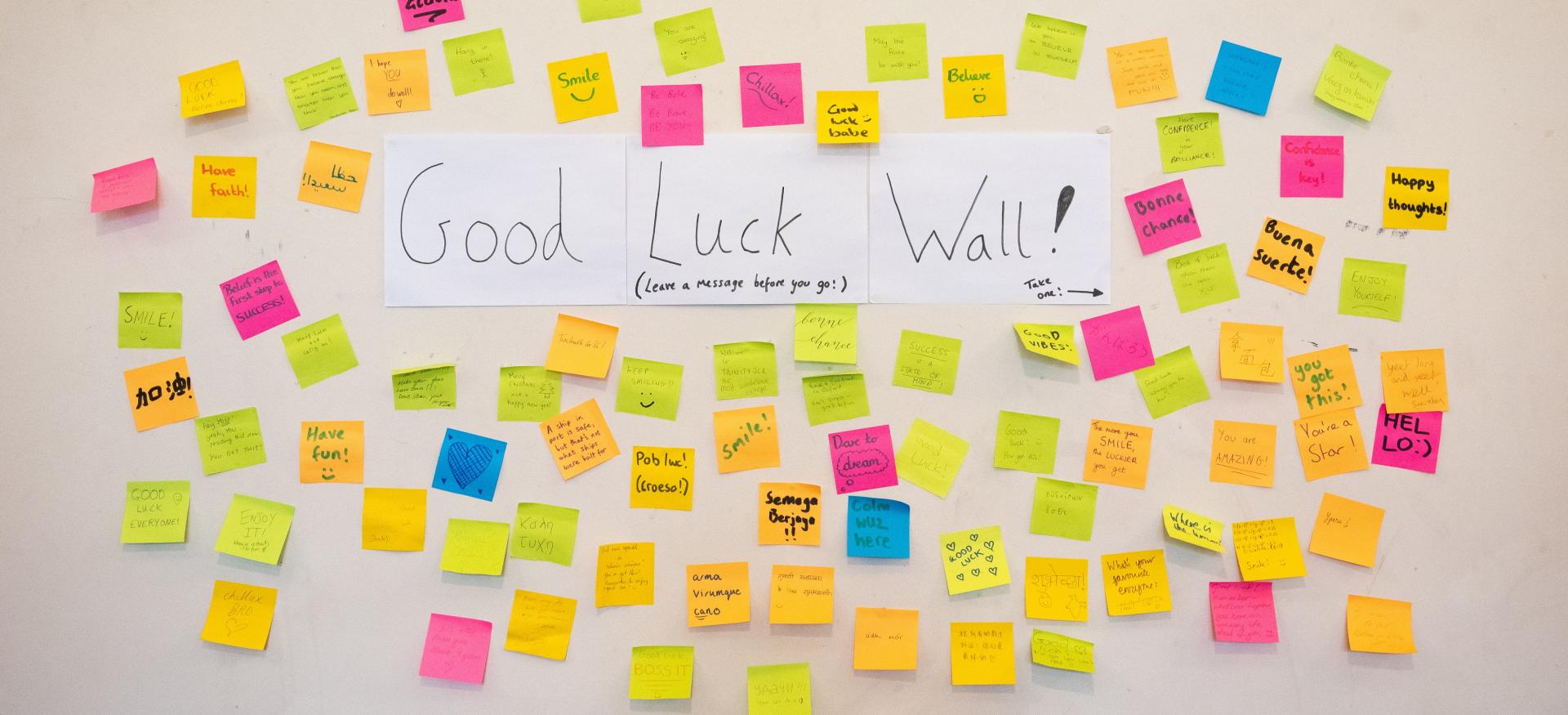 A wall with coloured sticky notes showing messages of support and "Good Luck Wall" written in the middle