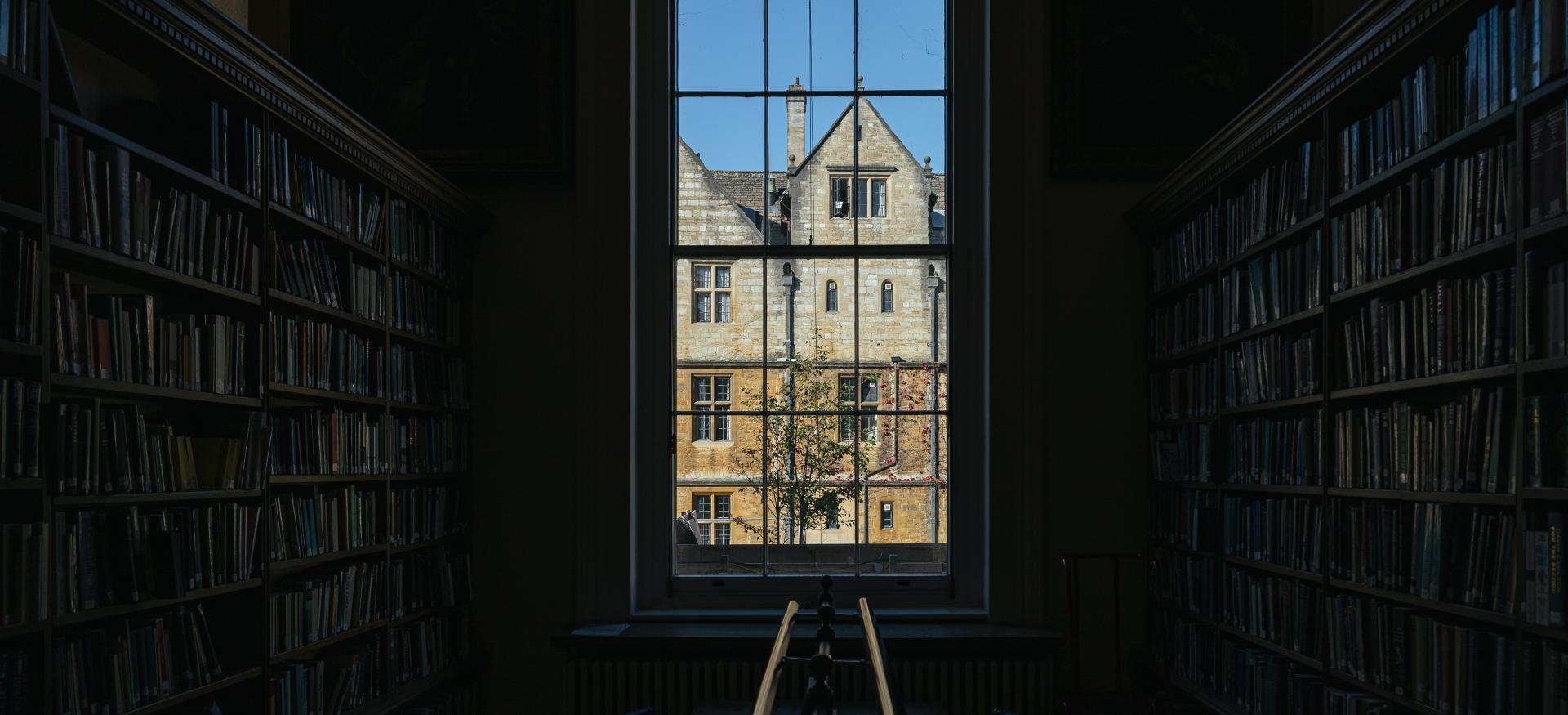 A view out of a dark interior of the Trinity library of the buildings across the quad.