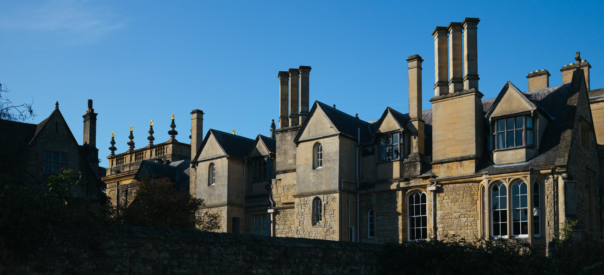 The tops of Trinity College buildings are visible against a blue sky and partially in shadow.
