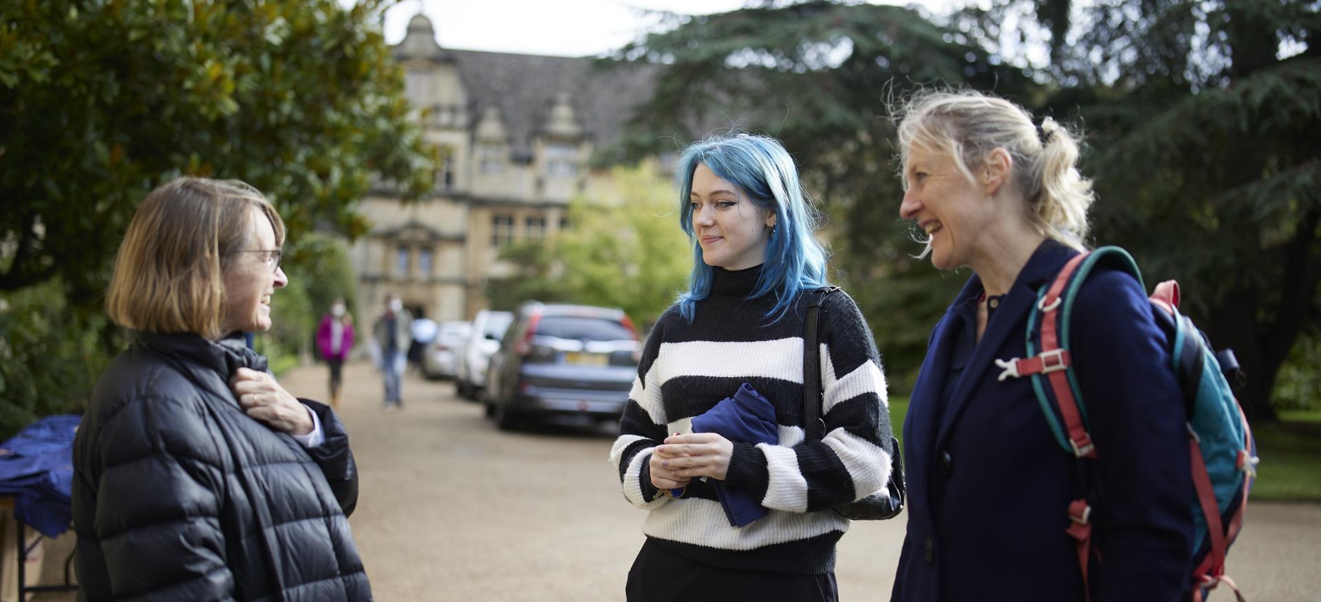 Two students chat with a chat member in Trinity's Front Quad.