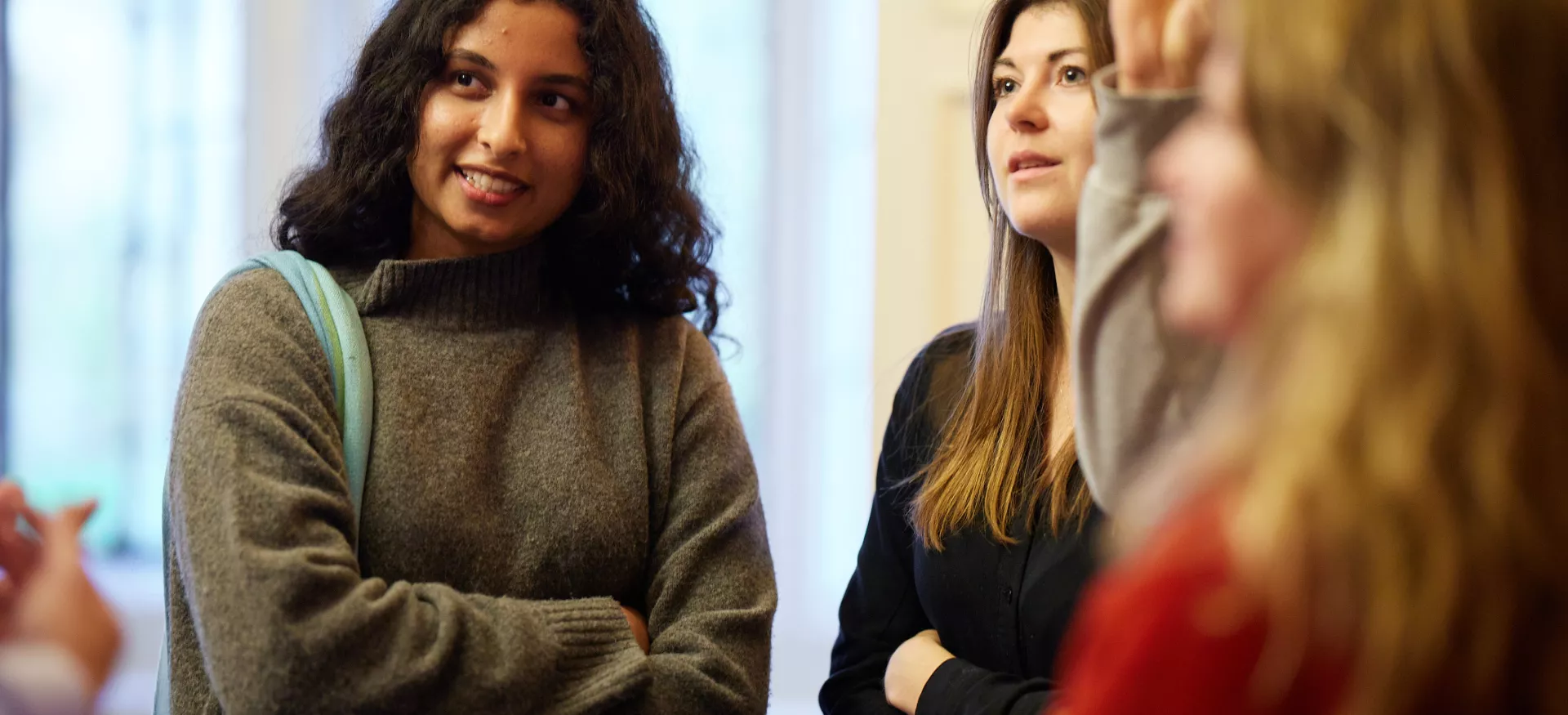 A group of female postgraduates smile and chat.