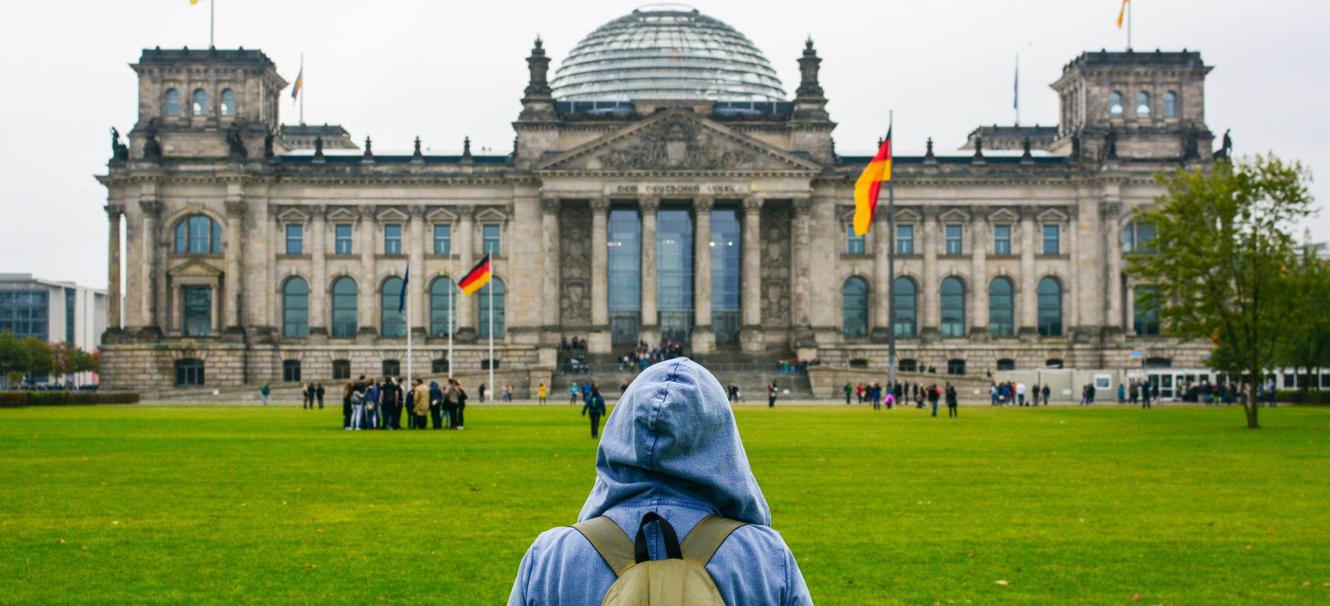 A young woman with backpack looking at Bundestag building in Berlin.