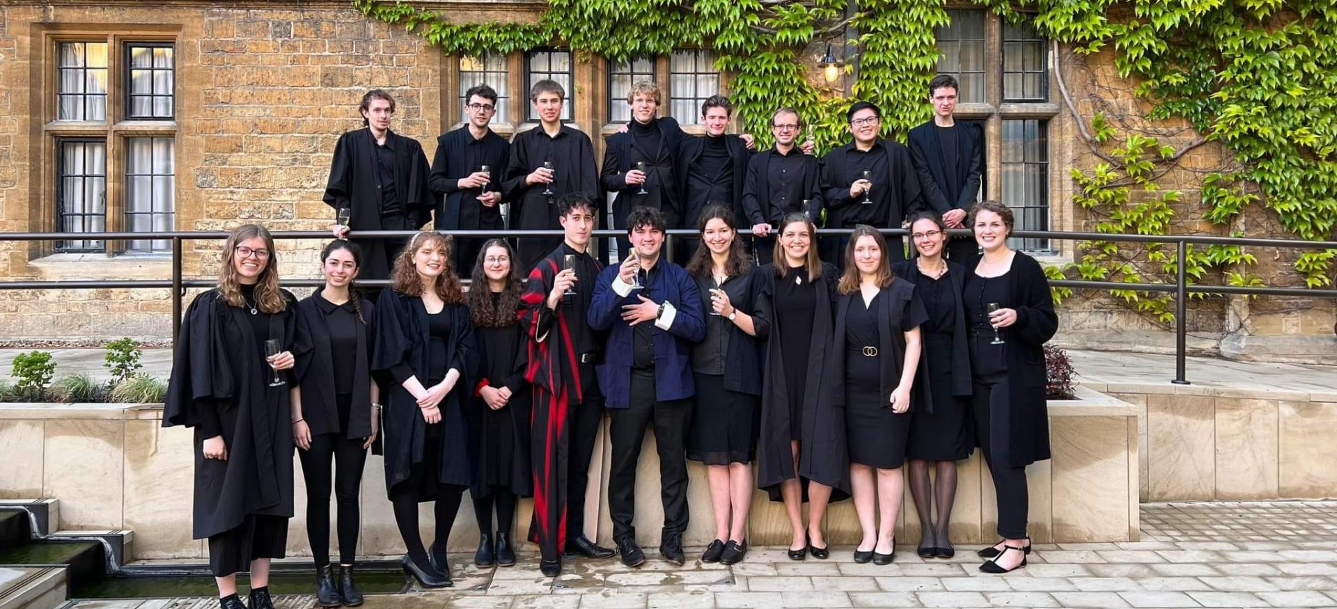The Trinity College chapel choir pose in the library quad of Trinity colege in gowns.