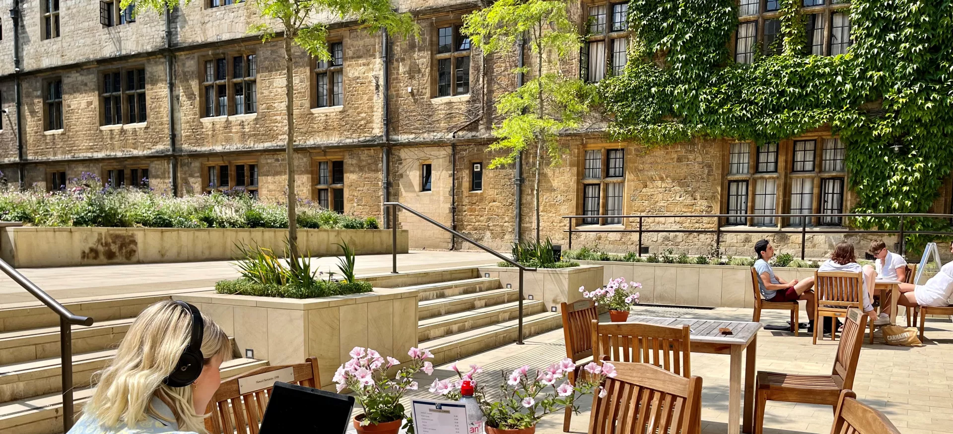 A student studies at a computer in the outdoor seating area outside Trinity's cafe.