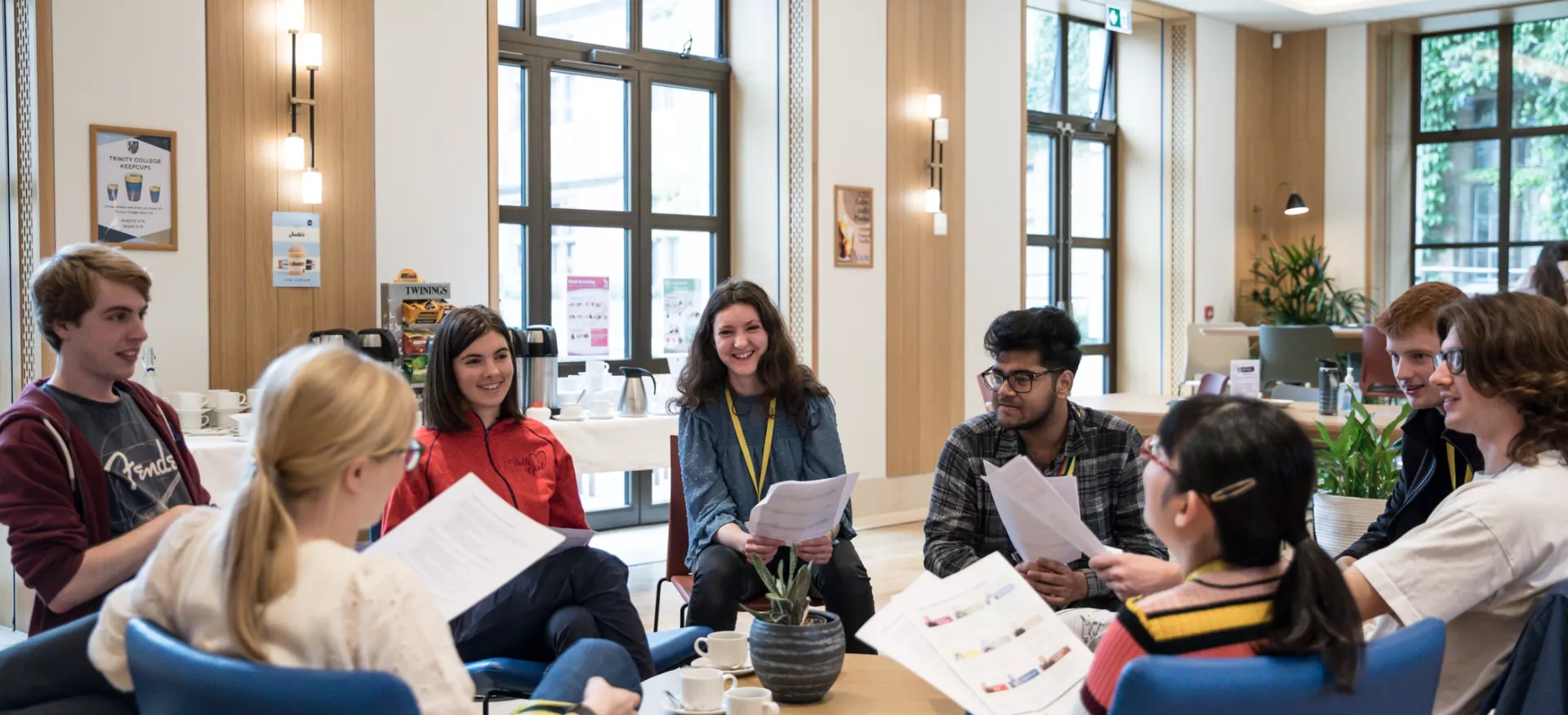 A group of students sit talking over worksheets in the Trinity college cafe.