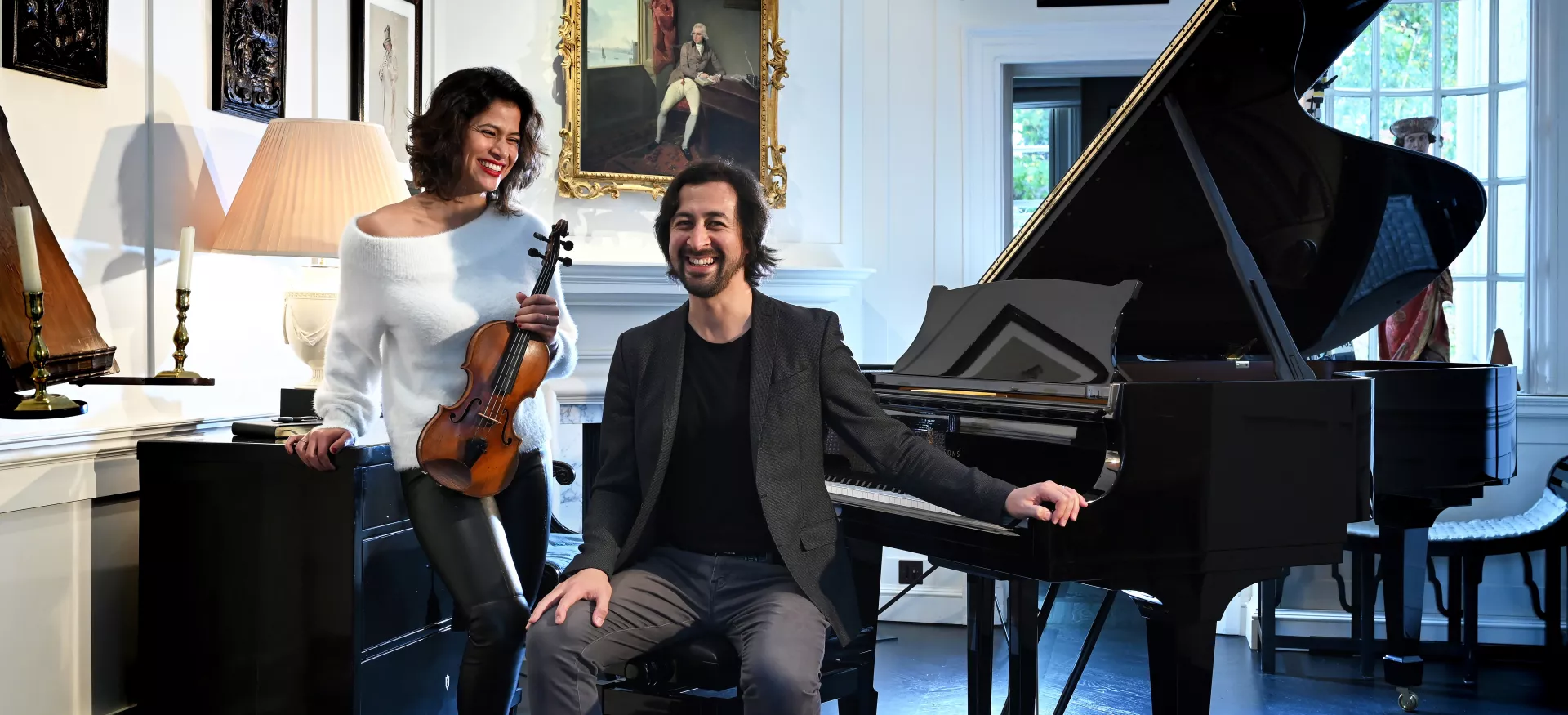 Elena Urioste and Tom Poster sit with their instruments in a drawing room.