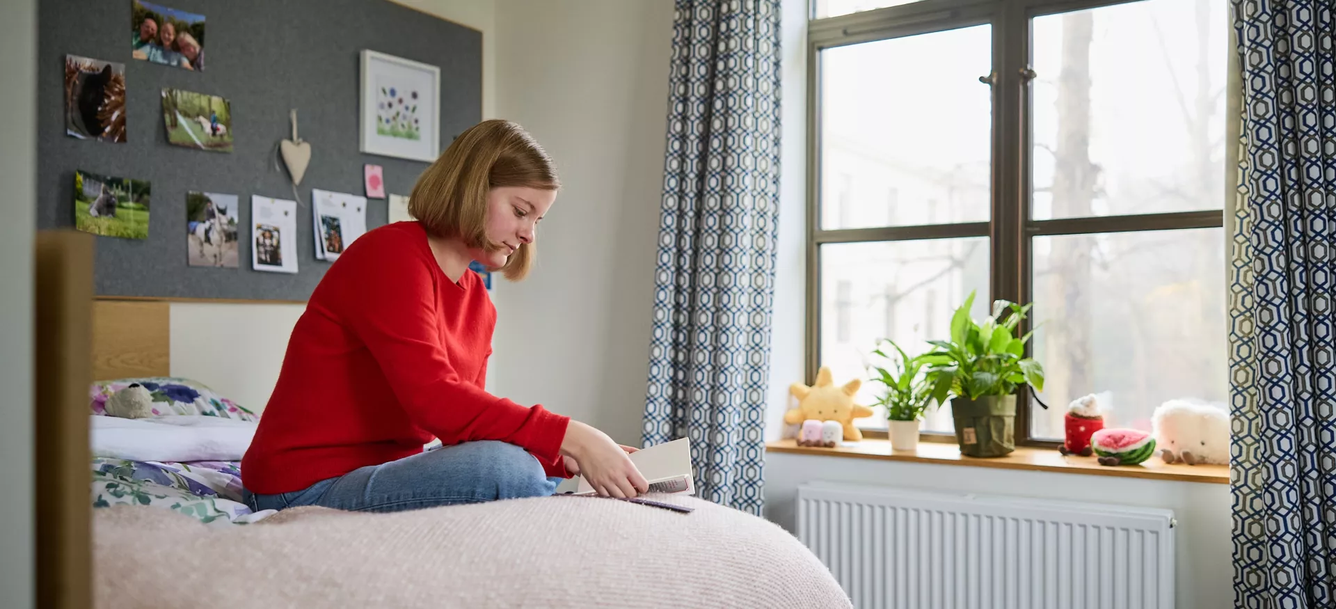 A female student sits reading on her bed in the Trinity College Levine Building.