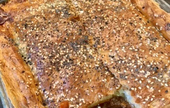 A beef, mushroom and ale pie cooked with a slice cut out.
