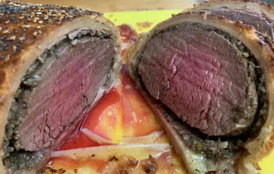 A beef wellington sliced in half revealing the meat in the middle.