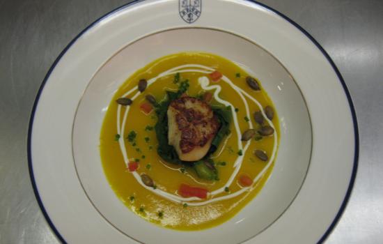 A bowl of buttnernut squash soup on a Trinity College plate.