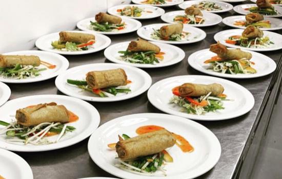 Three rows of plated food on a table ready to be served in the Trinity dining hall.