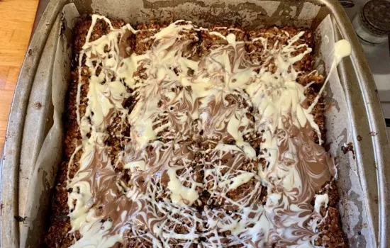 A tray of raspberry jam flapjack with chocolate drizzle.