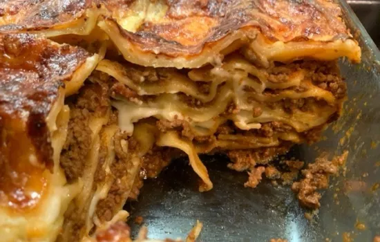 A tray of home-made lasagne with a slice cut out. 