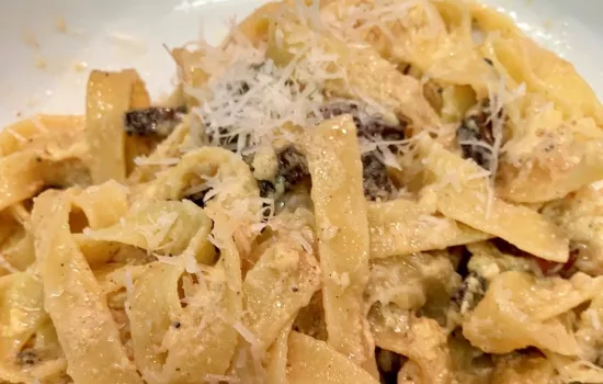 Close-up of a pile of pasta carbonara with grated cheese on top.
