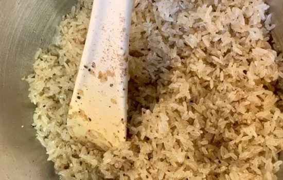 Pilau rice being mixed in a bowl.