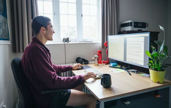 A postgraduate student sits studying at a desk. 