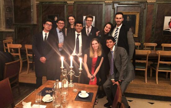 A group of Trinity College MCR students pose at formal hall in the dining hall.