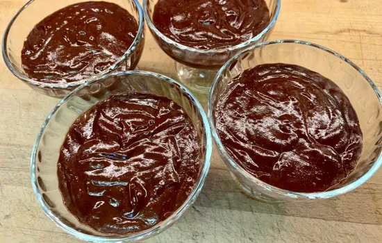 Four bowls of chocolate mousse sit on a table.