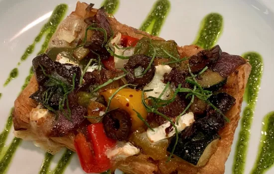 A finished vegan tart drizzled with pesto and plated.