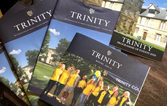 A group of Trinity College alumni publications sit displayed on a table.