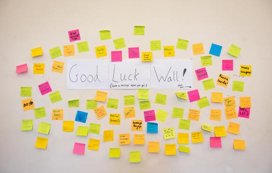 A wall with coloured sticky notes showing messages of support and "Good Luck Wall" written in the middle
