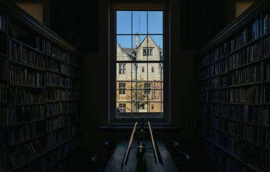 A view out of a dark interior of the Trinity library of the buildings across the quad.