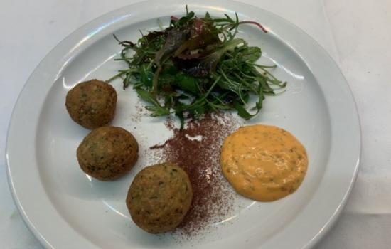 A plate of falafel with spiced mayonnaise and a leaf salad.