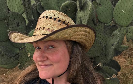 Kate Burtonwood in a straw cowboy hat with cacti in the background.