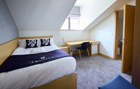 A view of a Trinity College guest room with bed made up.