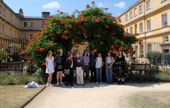 A group of students who participated in the Classics and the Ancient World Summer School stand in front of Trinity's Garden Quad arch.