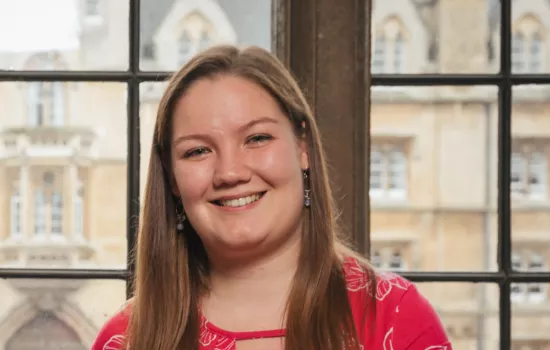 Eilidh Macfarlane smiles in front of a window in a college office in Trinity.