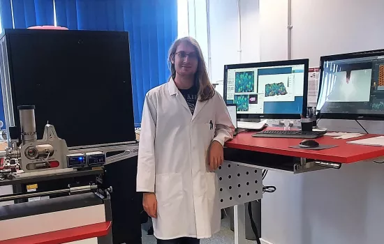 Martin Meier stands in his lab wearing a lab coat and goggles.