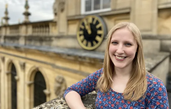 Emma Sillett stands in front of the Trinity Chapel clock.