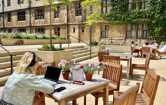 A student studies at a computer in the outdoor seating area outside Trinity's cafe.