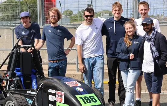 A group of Oxford students from the Oxford Racing team stand next to their electric vehicle at the Formula Student competition.