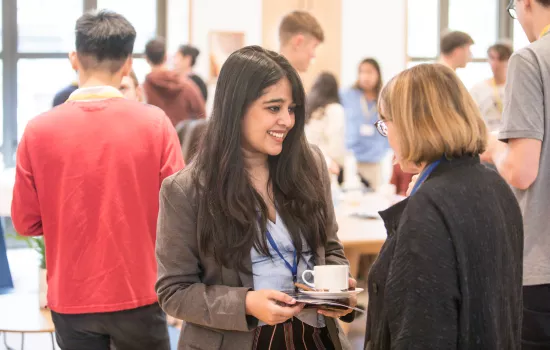 A Trinity College postgraduate student chats to the college president at an event in the college cafe.