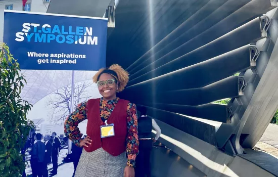 Luisa Costa stands in front of a sign for the St Gallen Symposium.