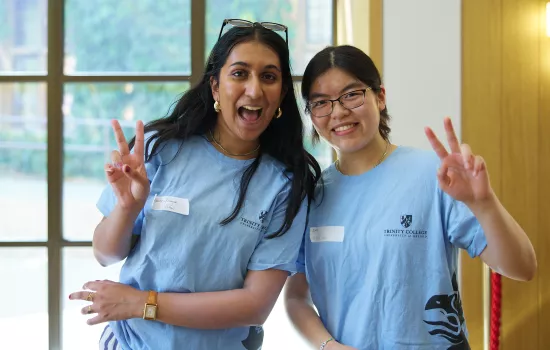Two Trinity College student ambassadors flash peace signs.