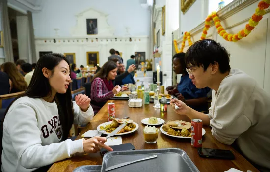 A group of students sit in the Trinity Dining hall eating during the Diwali themed meal in college.
