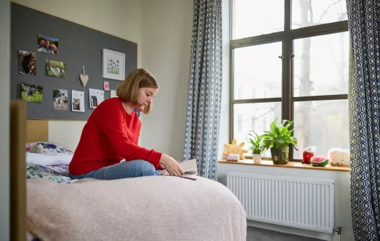 A female student sits reading on her bed in the Trinity College Levine Building.
