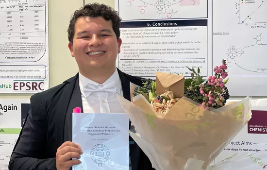 Trinity DPhil student Kam Poon stands holding flowers after his doctoral dissertation defence.