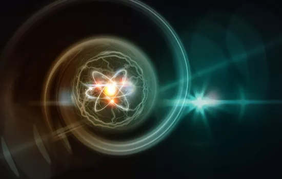 Digital illustration of an atom with glowing electrons orbiting a bright nucleus, surrounded by swirling energy and light flares on a dark background. 